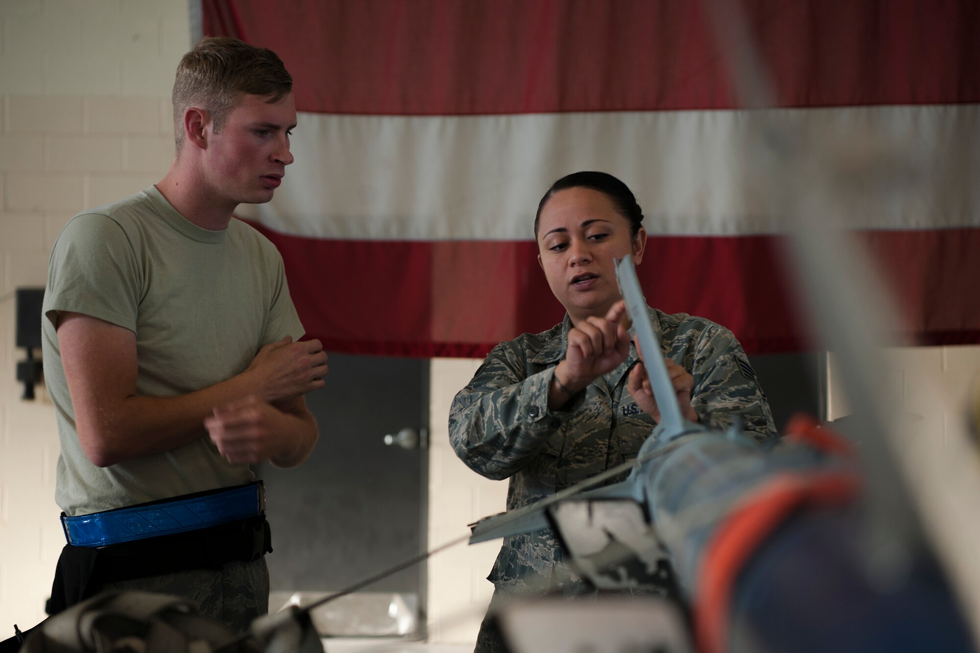 Staff Sgt. Raynette Hardcastle, right, 23d Maintenance Group lead crew chief, teaches Senior Airman Robert Monk, 23d Aircraft Maintenance Squadron weapons load crew member, during a Monthly Proficiency Required Load (MPRL), Aug. 7, 2018, at Moody Air Force Base, Ga. The weapons standardization section ensures weapons load crews are combat ready through evaluations consisting of MPRLs, semi-annual evaluations and flightline inspections. (U.S. Air Force photo by Airman Taryn Butler)