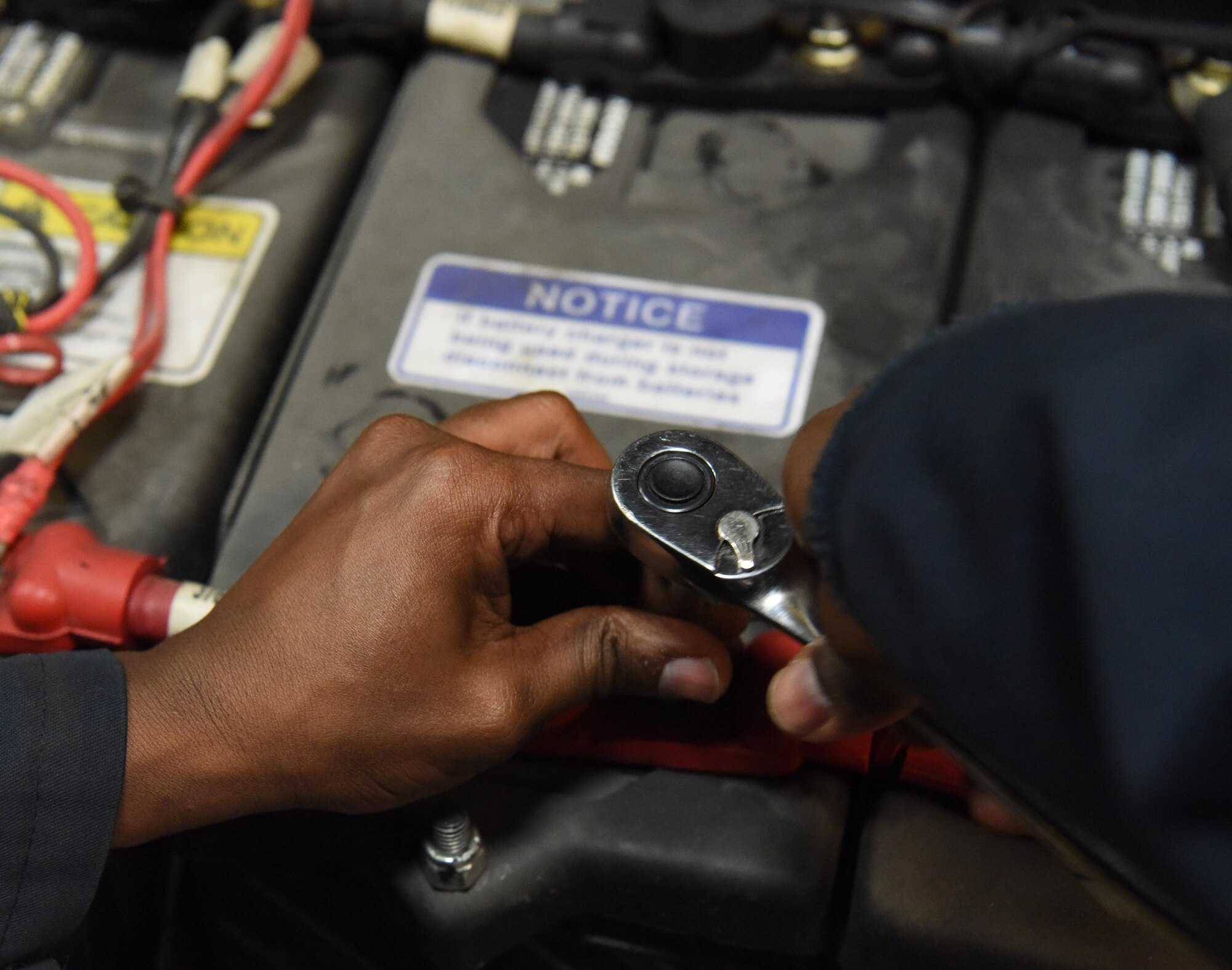 Airman 1st Class Victor Gathara, a 28th Logistics Readiness Squadron vehicle maintenance technician, connects a wire to a battery on a snow removal vehicle at Ellsworth Air Force Base, S.D., Aug. 9, 2018. Members of the 28th LRS vehicle maintenance shop perform a rebuild during the summer months on all the base’s snow fleet vehicles to ensure they are ready to operate effectively when winter arrives. (U.S. Air Force photo by Airman 1st Class Thomas Karol)