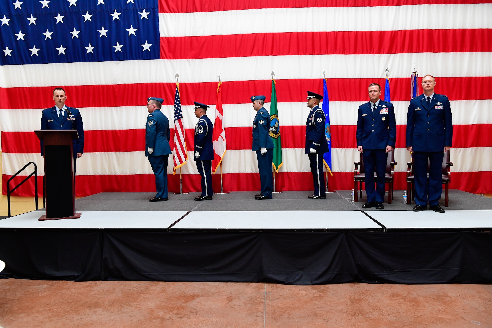 The Western Air Defense Sector Honor Guard post the colors during the WADS assumption of command ceremony at the Washington Army National Guard Readiness Center, Joint Base Lewis-McChord, Washington, July 31, 2018.  The new commander, Col. Gregory Lewis (right), stands beside the presiding officer, Brig. Gen. Kenneth Ekman, First Air Force and Air Forces Northern Command vice commander.