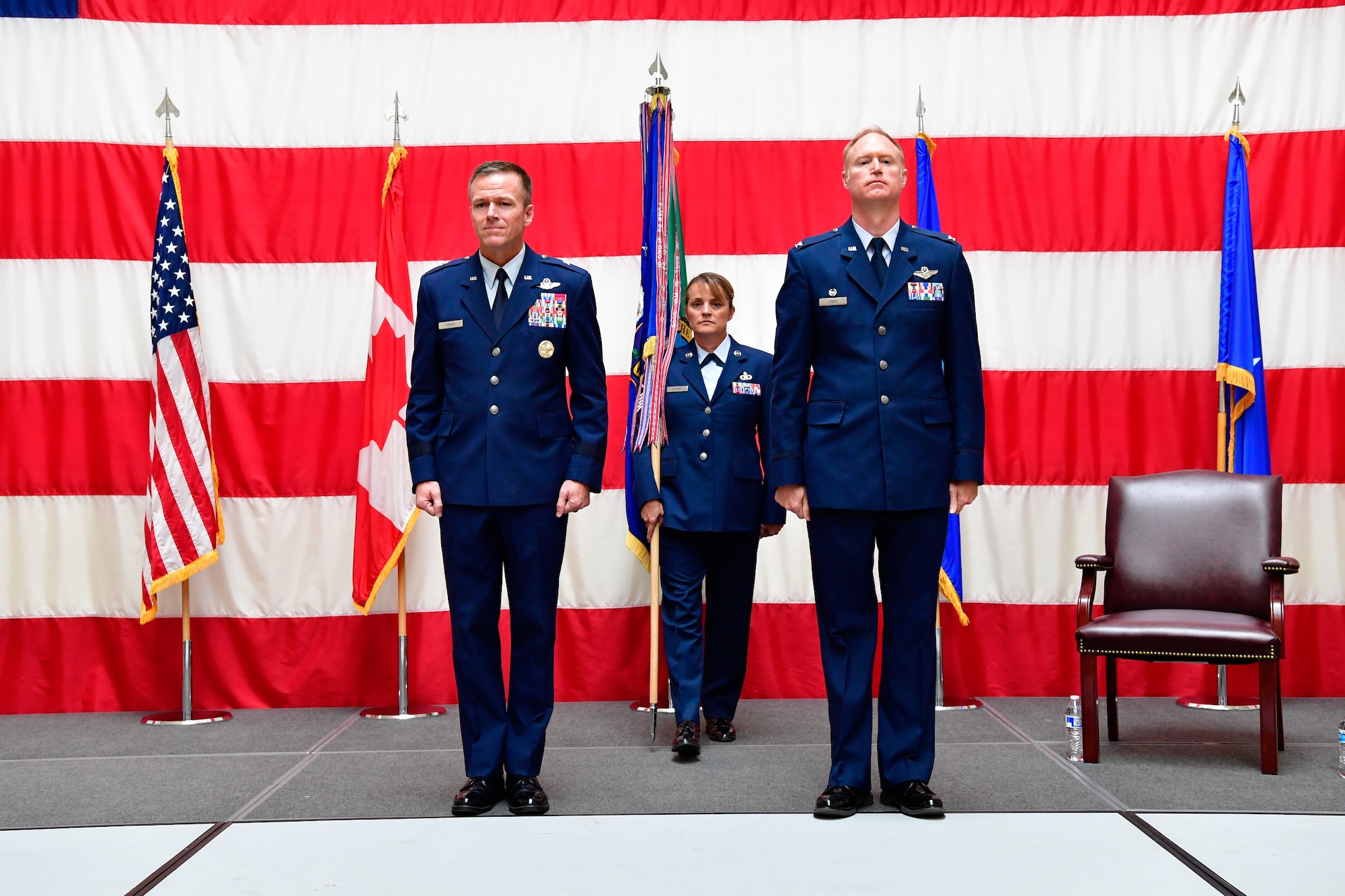 The Western Air Defense Sector first sergeant, Master Sgt. Mary Whitney, steps forward to present the unit colors to the WADS assumption of command presiding officer Brig. Gen. Kenneth Ekman (left), First Air Force and Air Force Northern Command vice commander.  Col.  Gregory Lewis (right) became the new commander of the Western Air Defense Sector July 31, 2018.