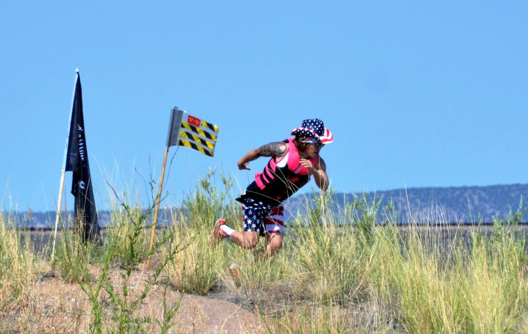 One of the participants heads back to his boat after planting his team flag on the island during the annual Cardboard Regatta at Cochiti Lake, July 27, 2018.