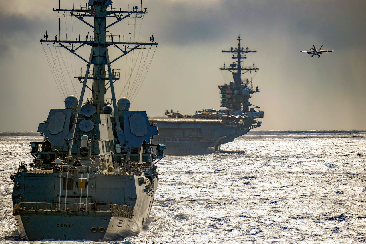 An airplane lands on an aircraft carrier in the water.