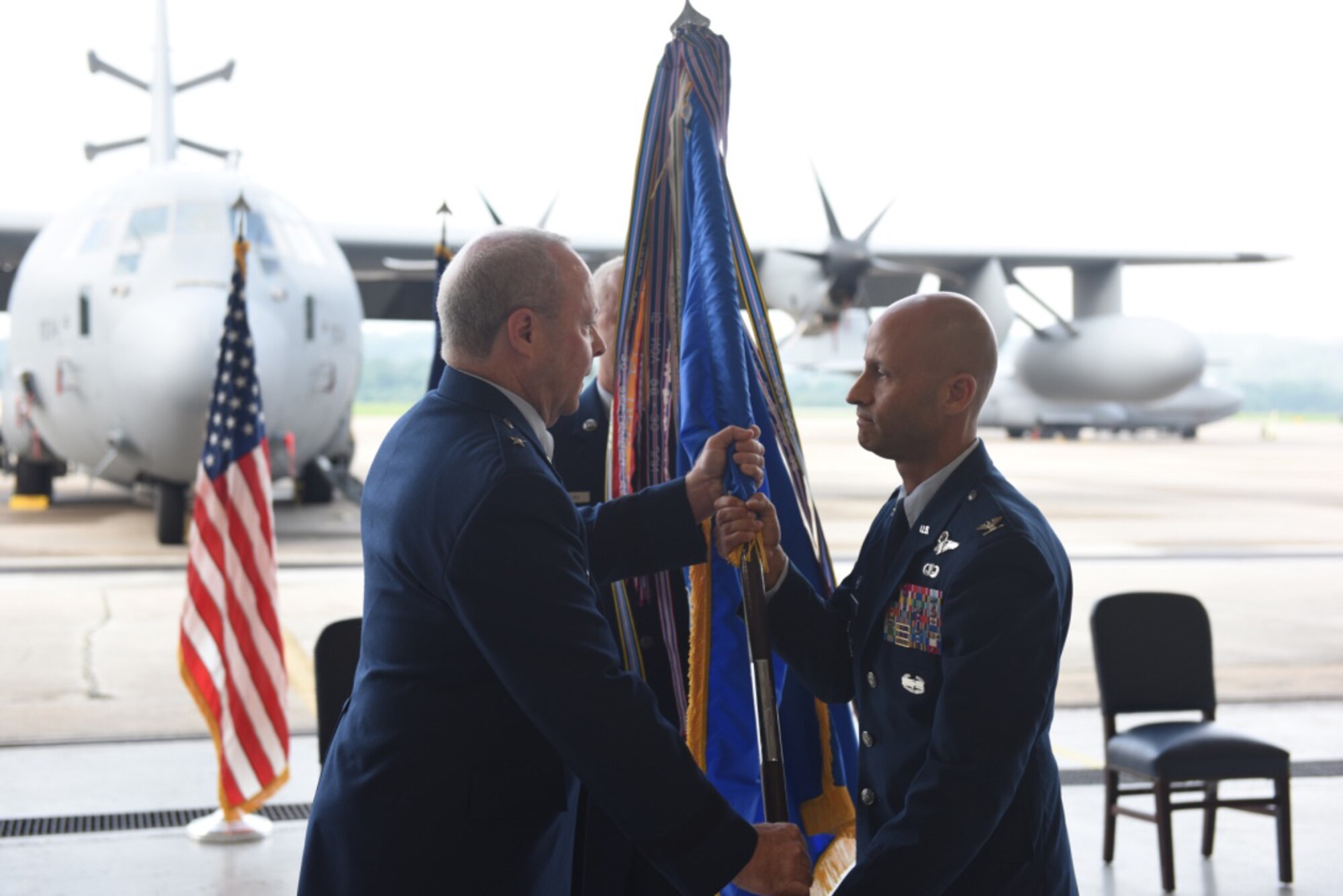 U.S. Air Force Col. Terrence Koudelka (right), receives the 193rd Special Operations Wing guidon from Brig. Gen. Mike Regan, Deputy Adjutant General - Air (left) during an assumption of command ceremony on base Aug. 11, 2018. Koudelka, as commander, is now responsible for leading one of the most deployed wings in the Air National Guard. (U.S. Air National Guard photo by Senior Airman Julia Sorber/Released).