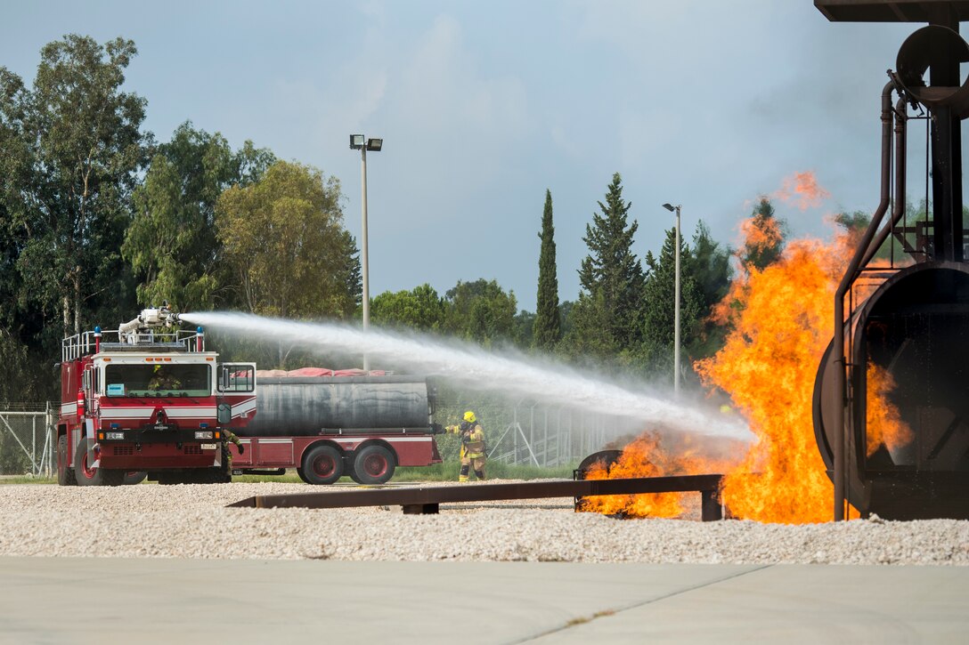 Fire truck sprays water at simulated aircraft fire.