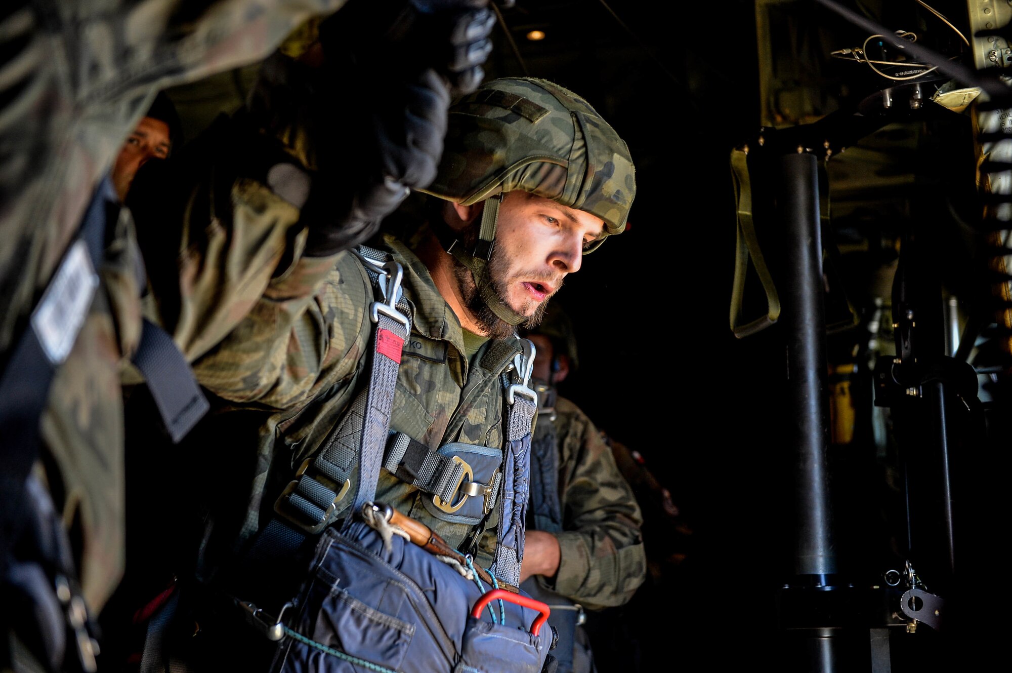 A Polish military paratrooper looks down over Poland as he prepares to jump from a U.S. Air Force C-130J Super Hercules Aug. 7, 2018. Two C-130Js assigned to the 86th Airlift Wing airdropped approximately 100 Polish troops as part of an annual bilateral exercise with the Polish military. (U.S. Air Force photo by Senior Airman Joshua Magbanua)