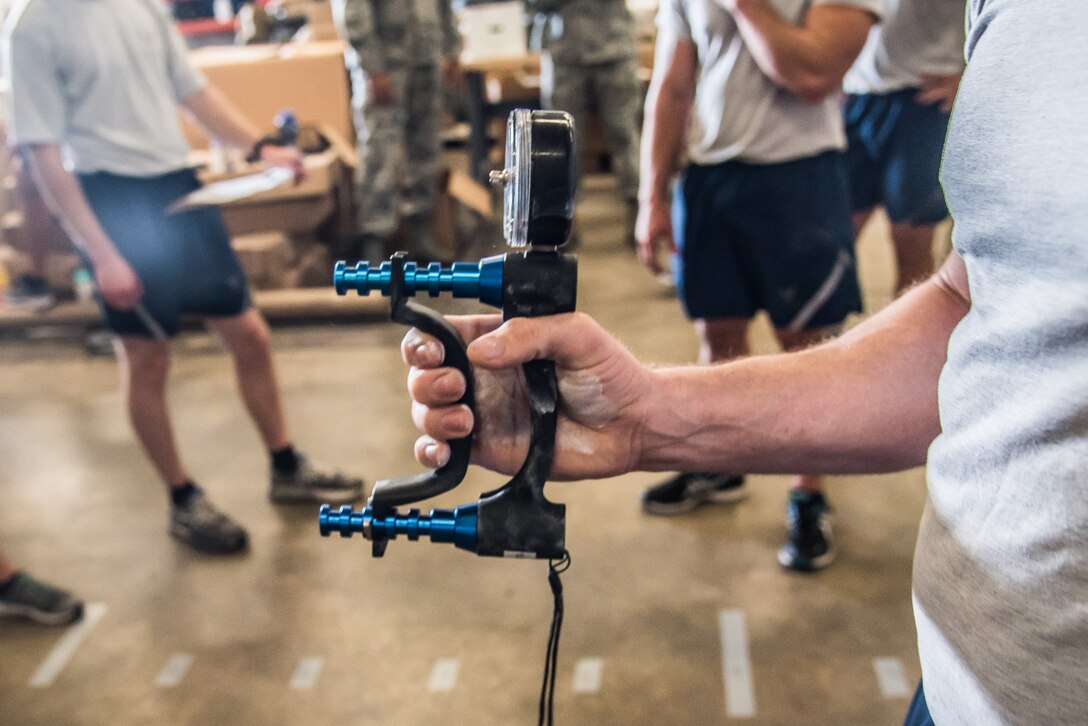 Master Sgt. Garth Muenter, the 512th Explosive Ordnance Disposal manager performs the Grip Strength component during the EOD Tier 2 Physical Fitness Test Prototype at Dover Air Force Base, Del., Aug. 8, 2018. EOD Airmen testing on the Grip Strength component are required to squeeze the dynamometer with maximum strength for two to three seconds. (U.S. Air Force photo by Staff Sgt. Damien Taylor)component are required to squeeze the dynamometer with maximum strength as hard as possible for two or three seconds. (U.S. Air Force photo by Staff Sgt. Damien Taylor)