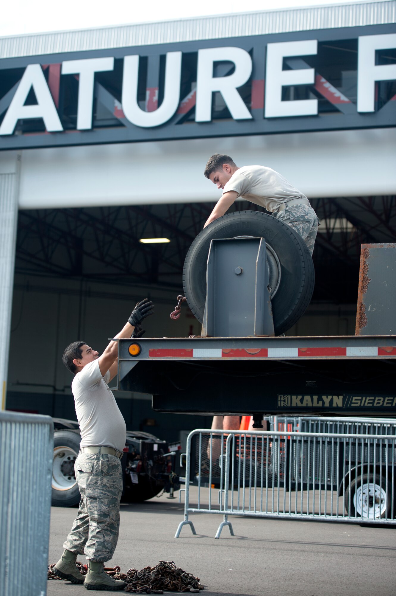 U.S. Air Force Airmen assigned to the 6th Logistics Readiness Squadron unload metal chains used to secure aircrew ground equipment assets from a trailer at Tampa International Airport, July 30, 2018.