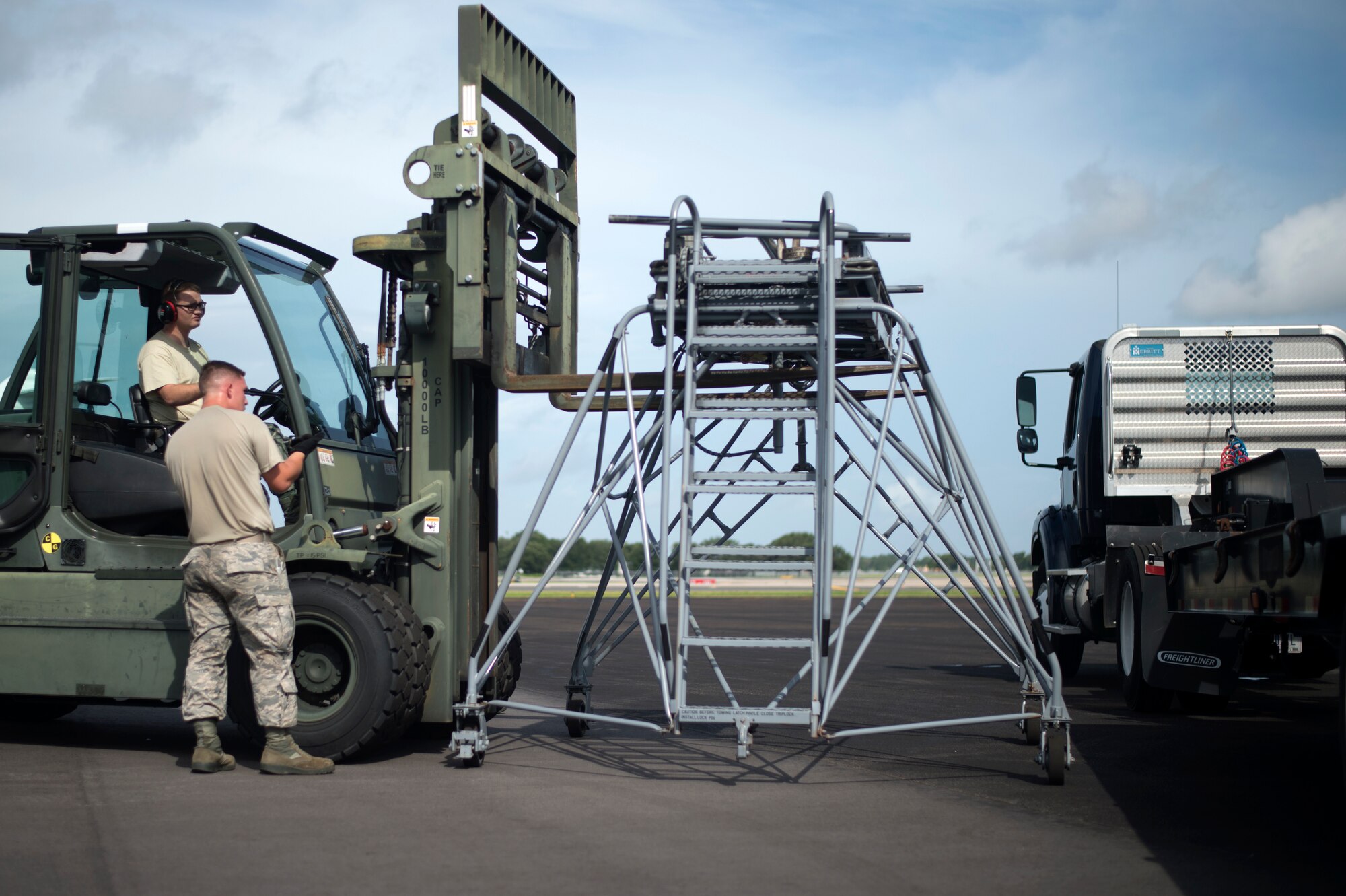 U.S. Air Force Staff Sgt. Landon Adams, training validation and operations NCO assigned to the 6th Logistics Readiness Squadron directs another Airman on how to load aircrew ground equipment (AGE) onto a trailer at Tampa International Airport (TIA) flightline, July 30, 2018.