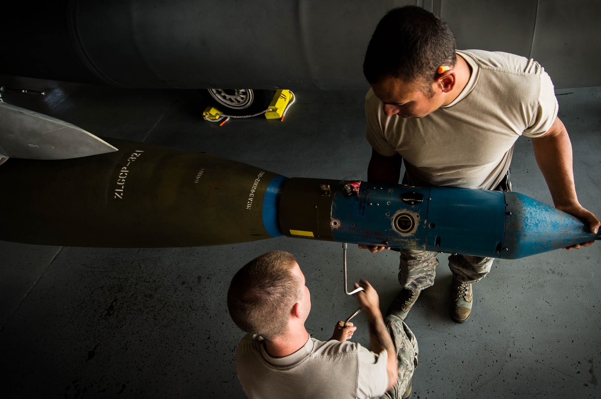 U.S. Air Force Senior Airman James Bridge, 77th Aircraft Maintenance Unit (AMU) load crew team member, left center, and Staff Sgt. Samuel Ortiz, 77th AMU load crew team lead, remove a CCG laser guided seeker from a GBU-10 at Shaw Air Force Base, S.C., Aug. 9, 2018.