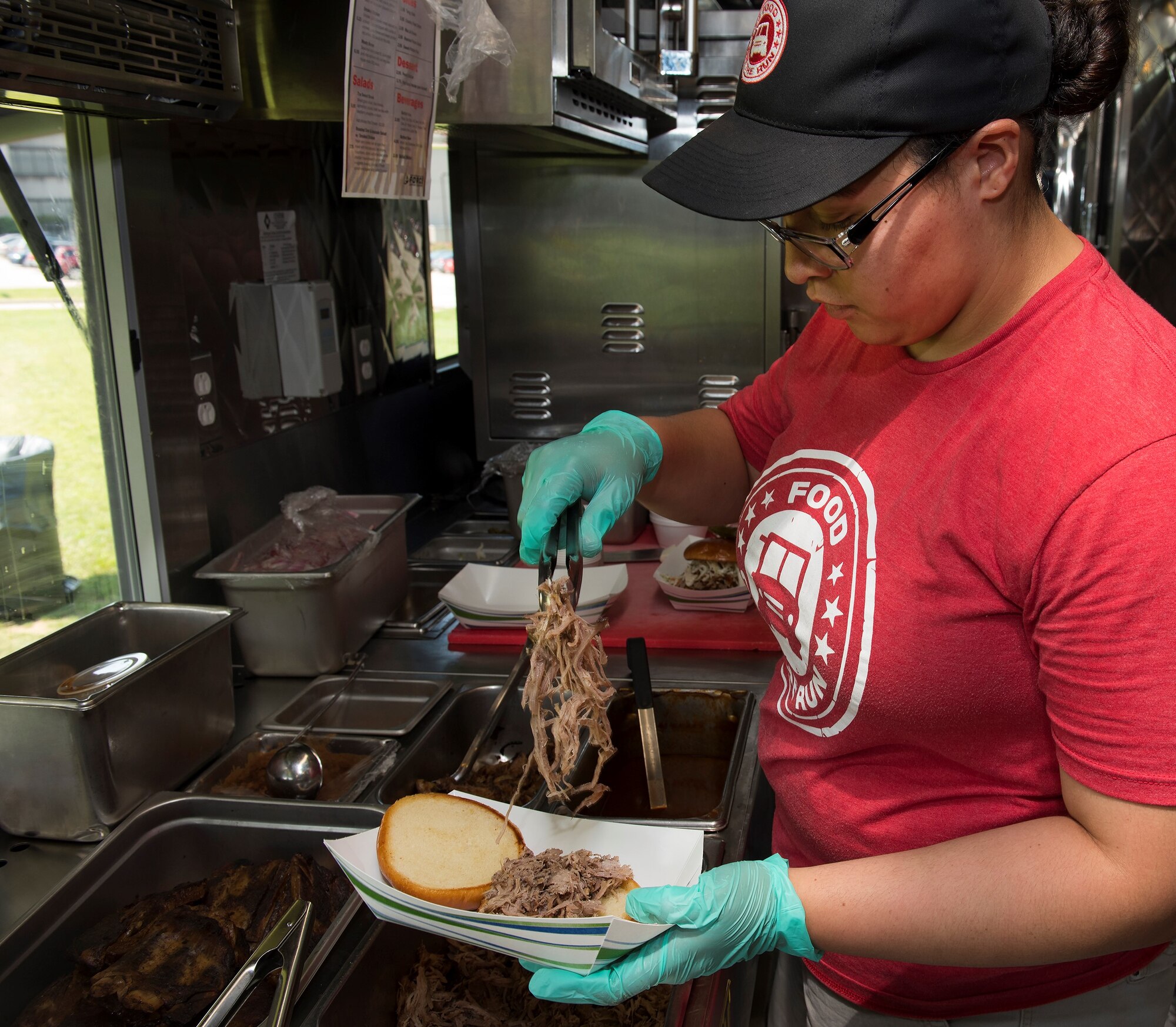 Ashley Huerta piles pulled pork onto a bun Aug. 3, 2018, in the 88th Force Support Squadron food truck "On the Run". The truck, operated by the Wright-Patterson Air Force Base, Ohio, club, rotates through menus including BBQ and Italian fare. (U.S. Air Force photo/R.J. Oriez)
