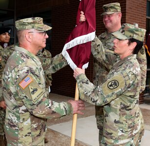 Maj. Gen. Barbara R. Holcomb (right), commanding general, U.S. Army Medical Research and Materiel Command and Fort Detrick, Maryland, presents the U.S. Army Institute of Surgical Research flag to USAISR’s new commander, Col. (Dr.) Jerome L. Buller (left) during a change of command ceremony July 19 at Joint Base San Antonio-Fort Sam Houston, as outgoing commander, Col. (Dr.) Shawn C. Nessen looks on.