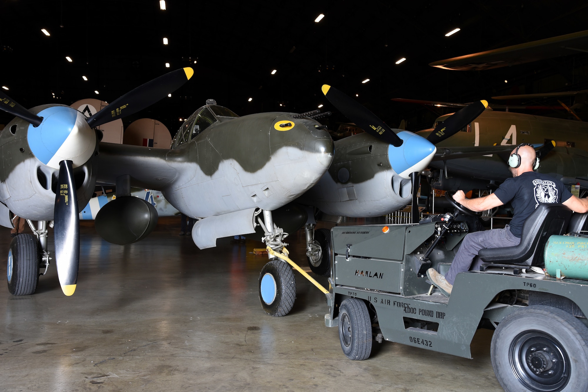 Chase Meredith, a museum restoration specialist at the National Museum of the U.S. Air Force, moves the Lockheed P-38L Lightning back into the WWII Gallery on Aug. 13, 2018. Several WWII era aircraft were temporarily placed throughout the museum to provide adequate space for the Memphis Belle exhibit opening events. (U.S. Air Force photo by Ken LaRock)