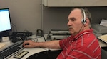 Man wearing headphones, sitting at a desk.
