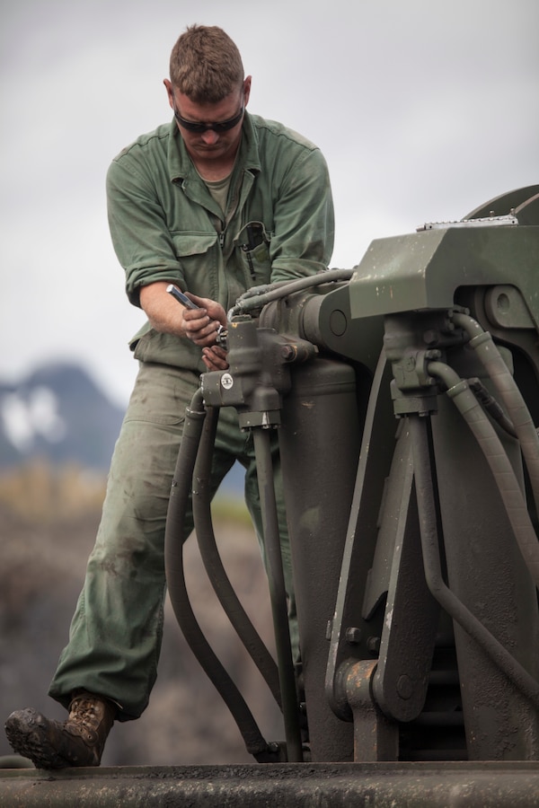 Lance Cpl. Daylan Wright, a heavy equipment mechanic with Headquarters Battery, 14th Marine Regiment, 4th Marine Division places the hydraulic housing of one of the rear main cylinders of a wheel tractor-scraper during Innovative Readiness Training, Old Harbor, Alaska, Aug. 5, 2018. This year marks the completion of the 2,000-foot extension of Old Harbor’s runway. (U.S. Marine Corps photo by Lance Cpl. Tessa D. Watts)