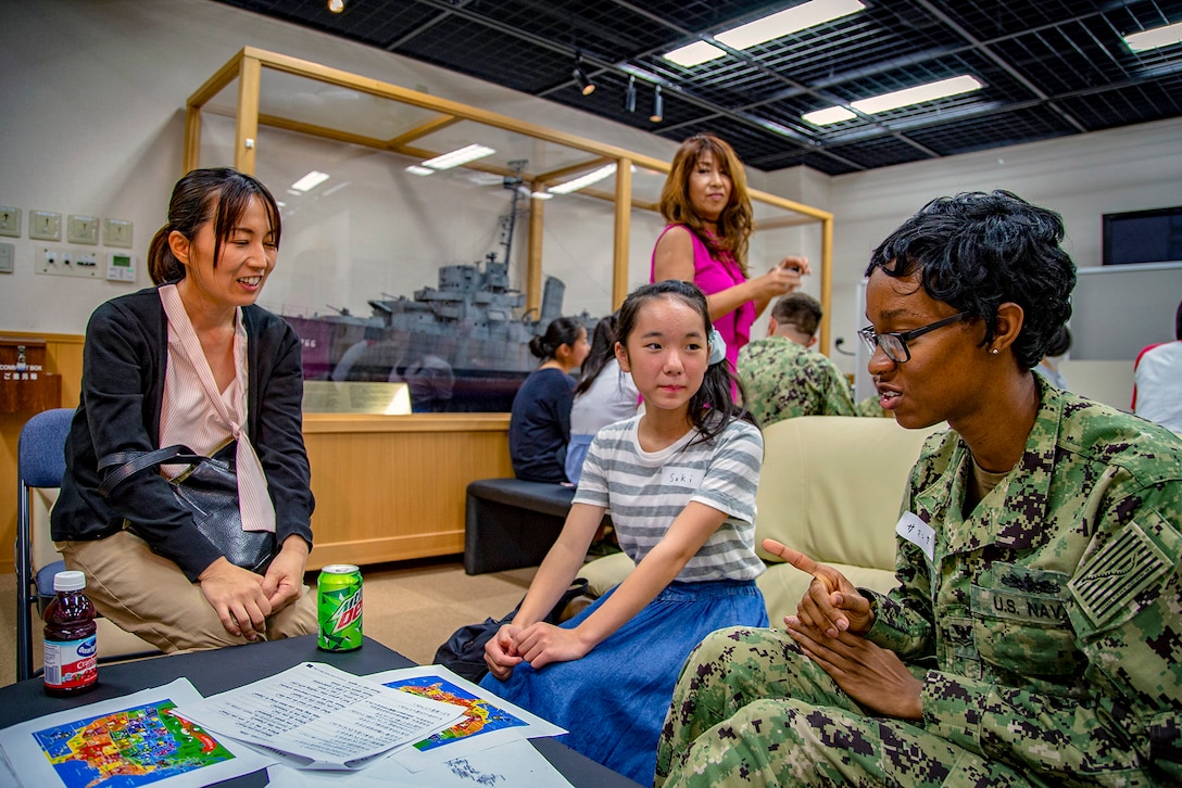 A sailor chats at a table with some Japanese citizens.