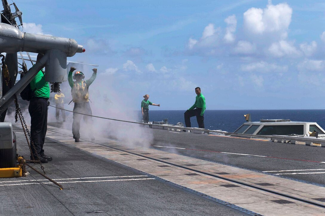 A sailor uses hand signals while conducting catapult operations.