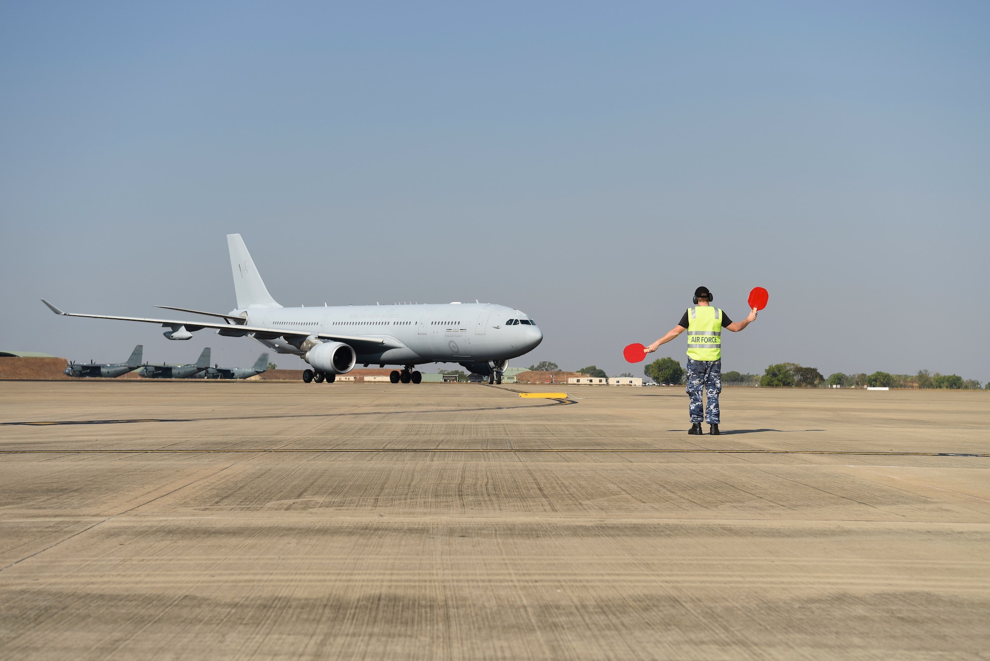 Royal Australian Air Force Aircraftsman Jordan Rees, 13th Squadron ground marshaller, directs a RAAF KC-30A Multi-Role Tanker Transport during exercise Pitch Black 2018, Aug. 8, 2018. This exercise aims to enhance flight operations and proficiency as well as maintain interoperability between the United States and partner nations. (U.S. Air Force photo by Senior Airman Savannah L. Waters)