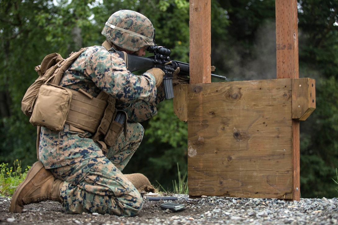 A Marine aims his rifle from the kneeling position.