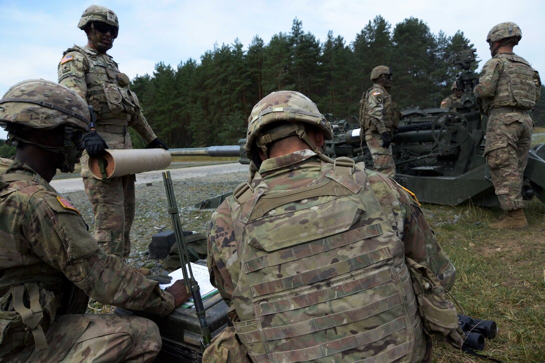 Soldiers receive orders before firing an M777A2 howitzer.