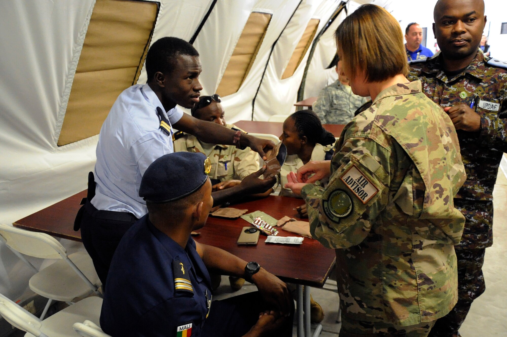Lt. Yassive Mahamat Brahim, a helicopter technician in the Chad air force, shares a Meal Ready to Eat with U.S Air Force Master Sgt. Emily Vaughn, a Personalist assigned to 818th Mobility Support Advisory Squadron during the African Partnership Flightat Ramstein Air Base, Germany, Aug. 9, 2018. The APF program is Air Forces in Africa's premier security cooperation program with African partner nations to improve professional military aviation knowledge and skills. (U.S. Army photo by Spc. Craig Jensen)