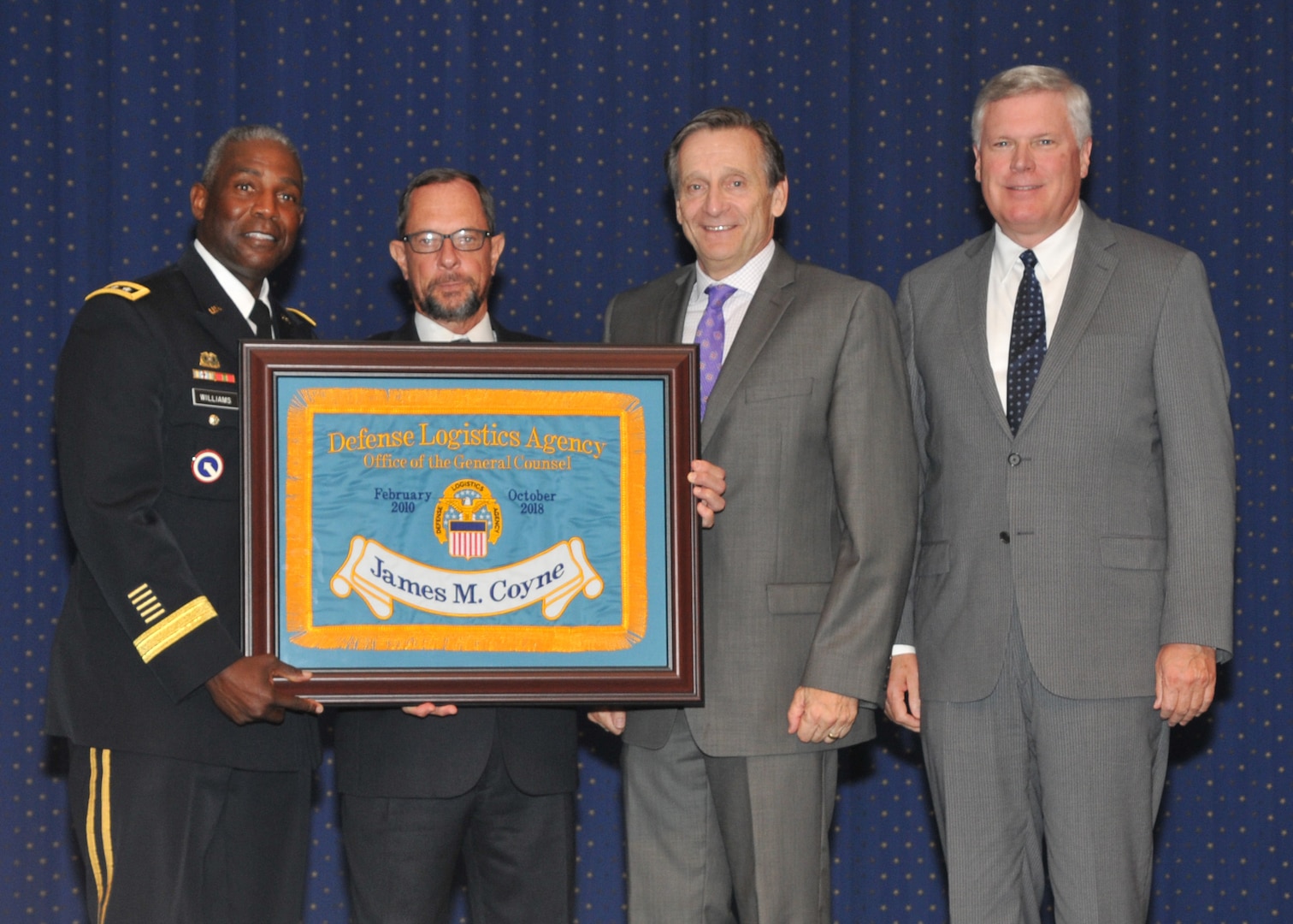 DLA Director Army Lt. Gen. Darrell Williams (far left) and former DLA directors Vice Adm. Mark Harnitchek (second from right) and Vice Adm. Alan Thompson (far right), present DLA General Counsel James Coyne an honorary DLA flag during his retirement ceremony Aug. 10 at the McNamara Headquarters Complex, Fort Belvoir, Virginia. Photo by Teodora Mocanu.