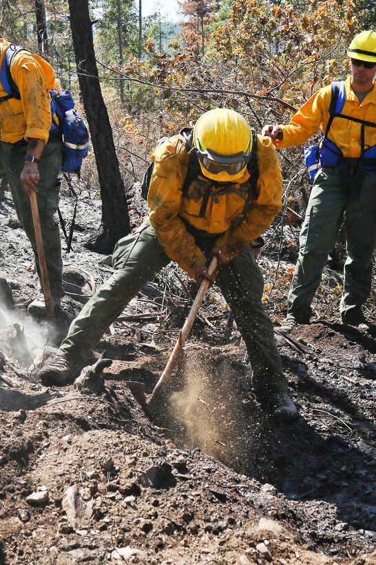 Oregon Army National Guardsmen and firefighters use shovels and pickaxes to fight a wildfire.
