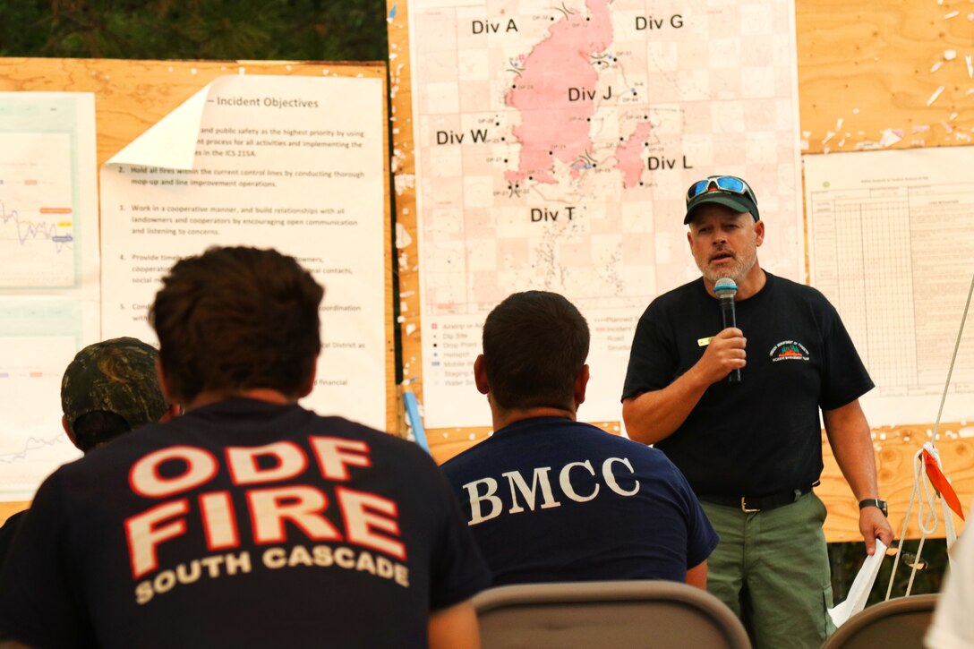 A firefighter briefs soldiers, firefighters and support staff.