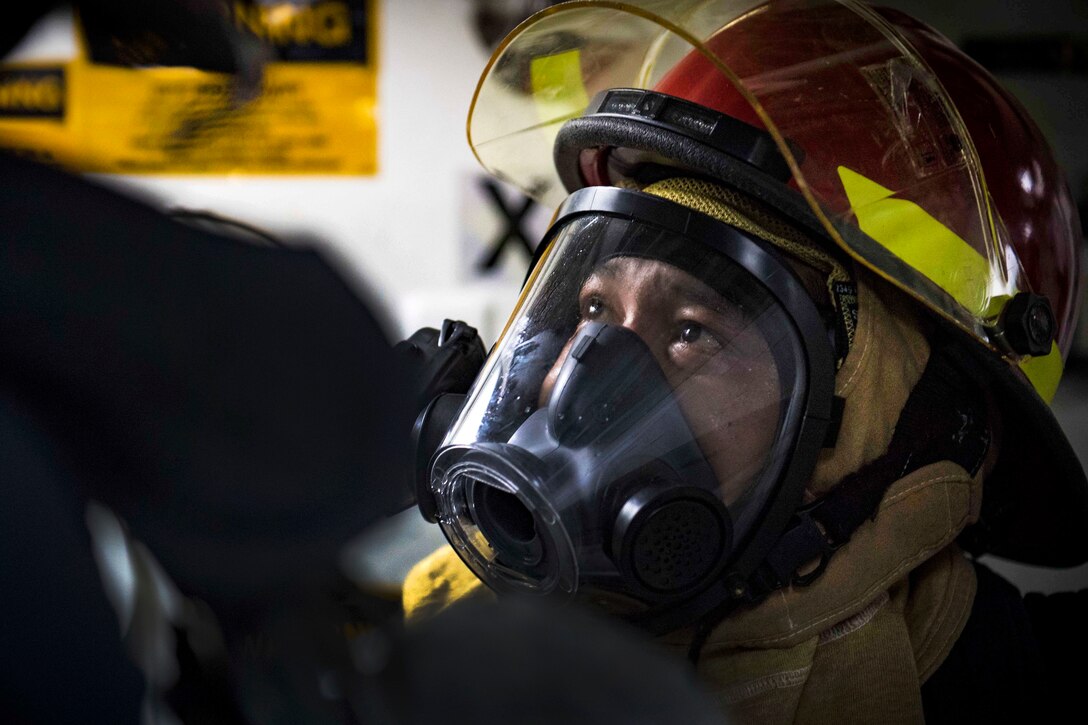 A sailor investigates for damage during a general quarters drill.