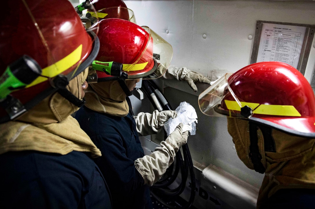 Sailors prepare to patch a damaged pipe during a general quarters drill.