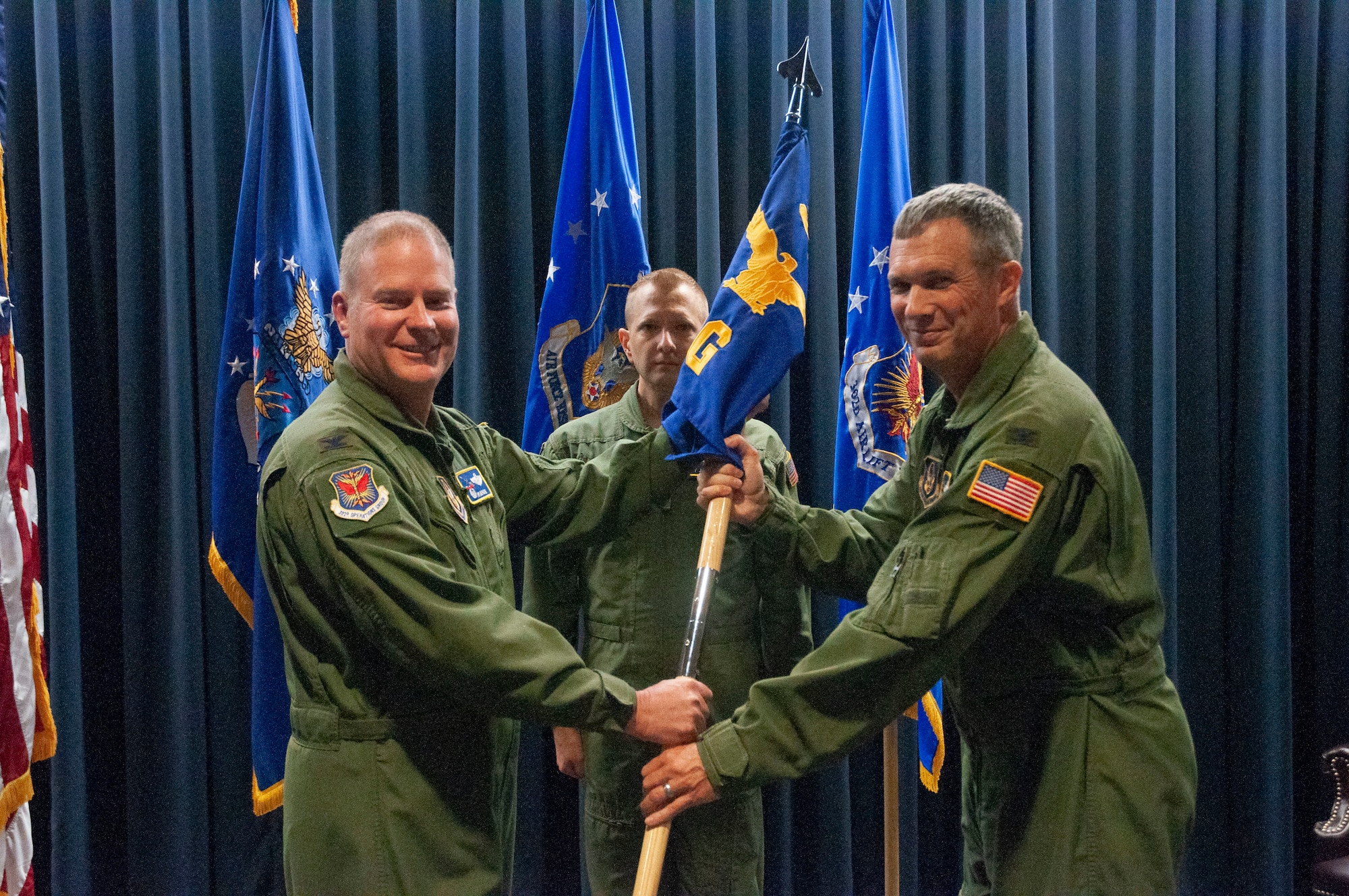 Col. Gregory Berry (right), the new 302nd Operations Group commander, accepts the 302nd OG guidon from Col. James DeVere (left), 302nd Airlift Wing commander, during an assumption of command ceremony at Peterson Air Force Base, Colorado, Aug. 4, 2018