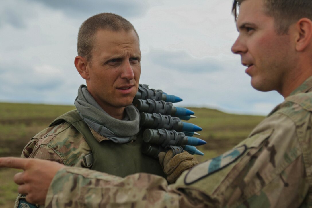 Two service members have a discussion during a military exercise.