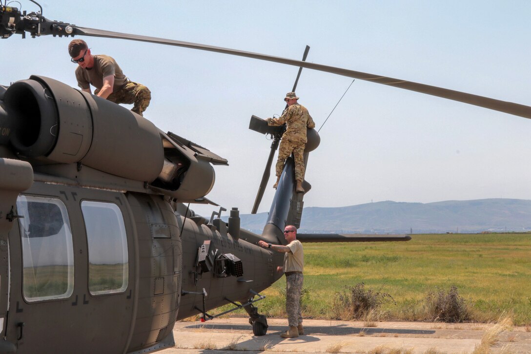 Army pilots perform preflight checks on a UH-60 Black Hawk helicopter.