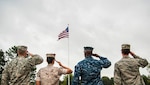 Service members salute the American flag during a retreat ceremony. The four military members represented each branch of the U.S. military and assembled to show solidarity.