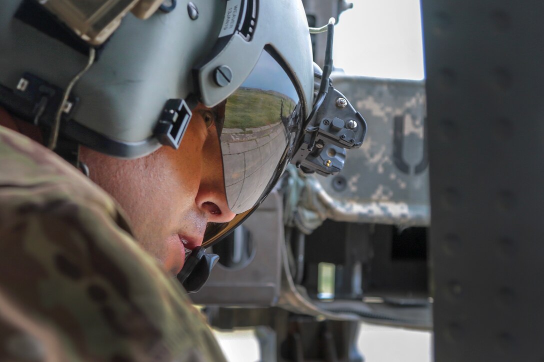 An Army crew chief checks for clearance out the side door of an UH-60 Black Hawk helicopter.