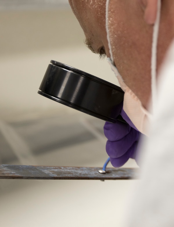 Timothy Kesterson, a latent print examiner, assigned to the Forensic Exploitation Laboratory – Central Command inspects a recovered piece of metal used as a pressure plate in an improvised explosive device uncovered in an undisclosed location in CENTCOM’s area of responsibility at Camp Arifjan, Kuwait, August 9, 2018. The FXL-C continually adapts and moves forward with emerging new technology to sustain a powerful and lethal combat force in the battleground.