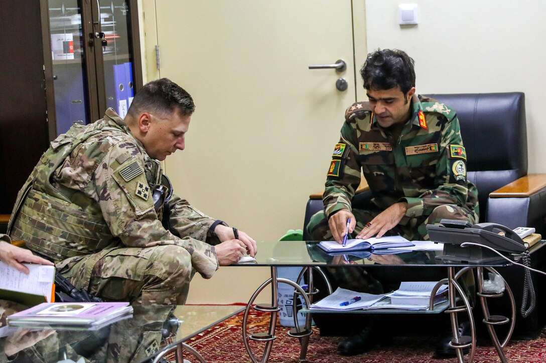 A sailor and an Afghan soldier exchange notes during a medical advisory visit.