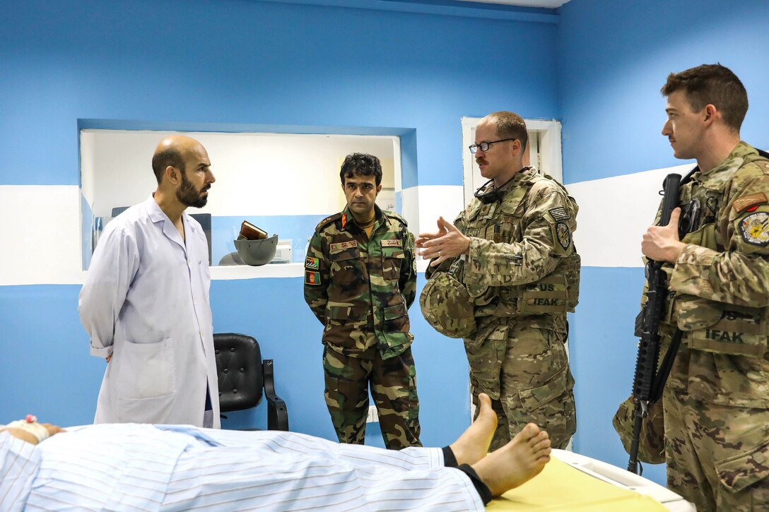 A sailor and an Afghan soldier talk during a medical advisory visit.