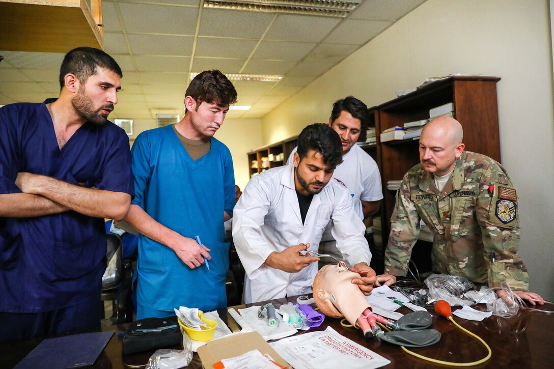 An American Navy nurse observes as Afghan medical staff members demonstrate how to open an airway.