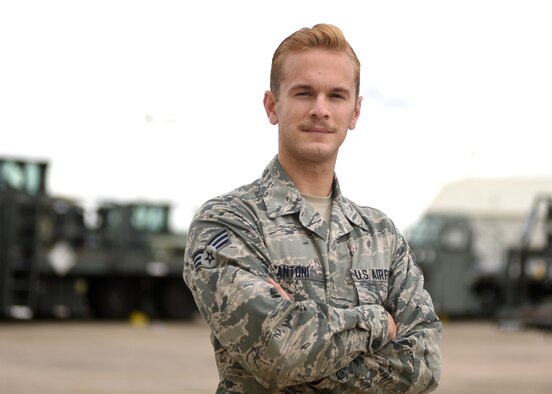 A male in uniform loads a grey C-130J with a vehicle.