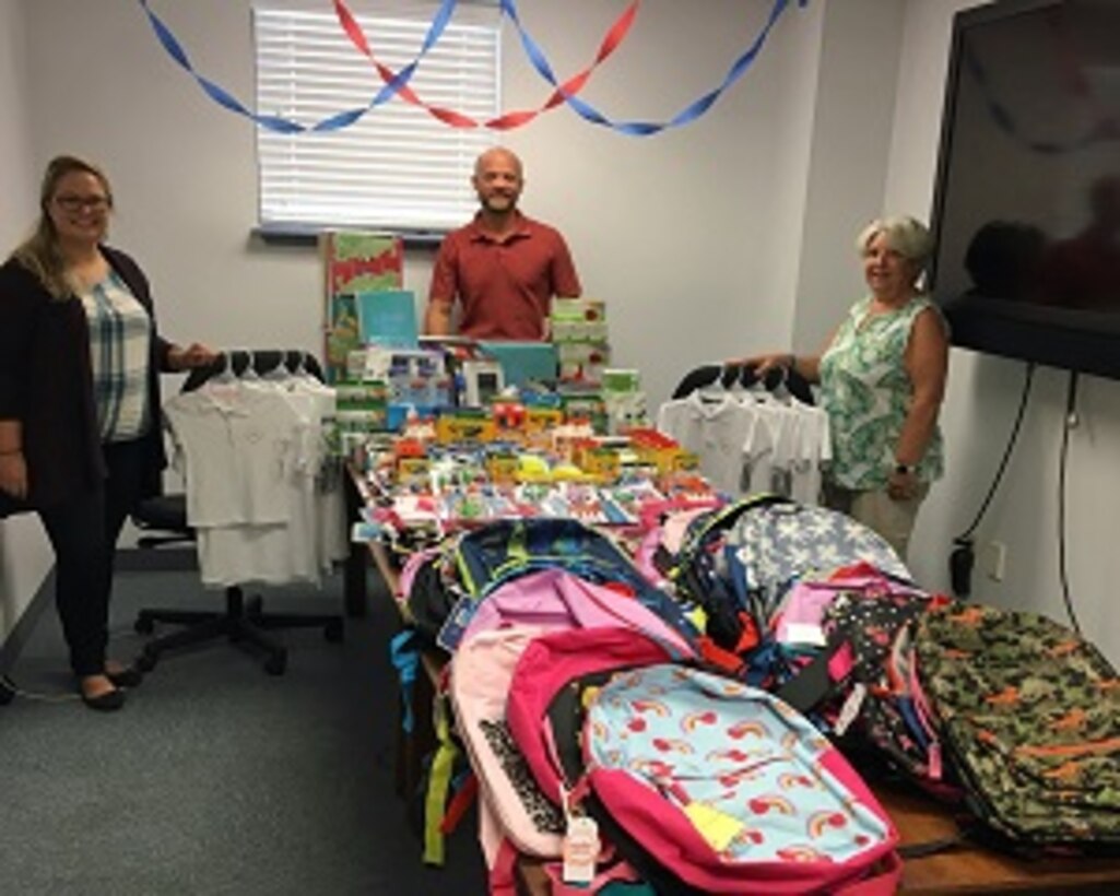 PANAMA CITY, Florida - Members of the Naval Surface Warfare Center Panama City Division (NSWC PCD) Test and Evaluation Prototype Fabrication Division share the assortment of school supplies to be donated. The group worked within their division to collectively provide supplies to children in need. Pictured from left to right: Nicole Waters, Dr. Ben Schlorholtz, and Paula Oliver. U.S. Navy photo by Susan H. Lawson