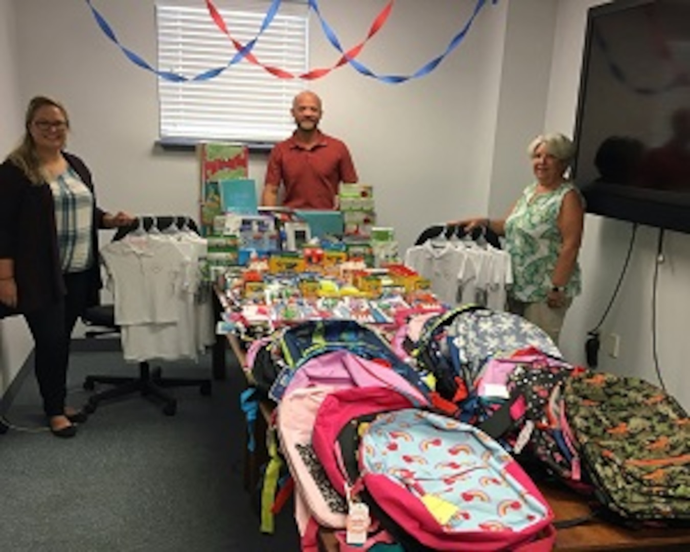 PANAMA CITY, Florida - Members of the Naval Surface Warfare Center Panama City Division (NSWC PCD) Test and Evaluation Prototype Fabrication Division share the assortment of school supplies to be donated. The group worked within their division to collectively provide supplies to children in need. Pictured from left to right: Nicole Waters, Dr. Ben Schlorholtz, and Paula Oliver. U.S. Navy photo by Susan H. Lawson
