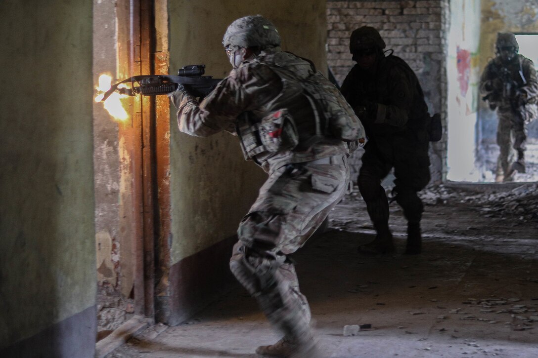 A soldier fires his weapon into a room.