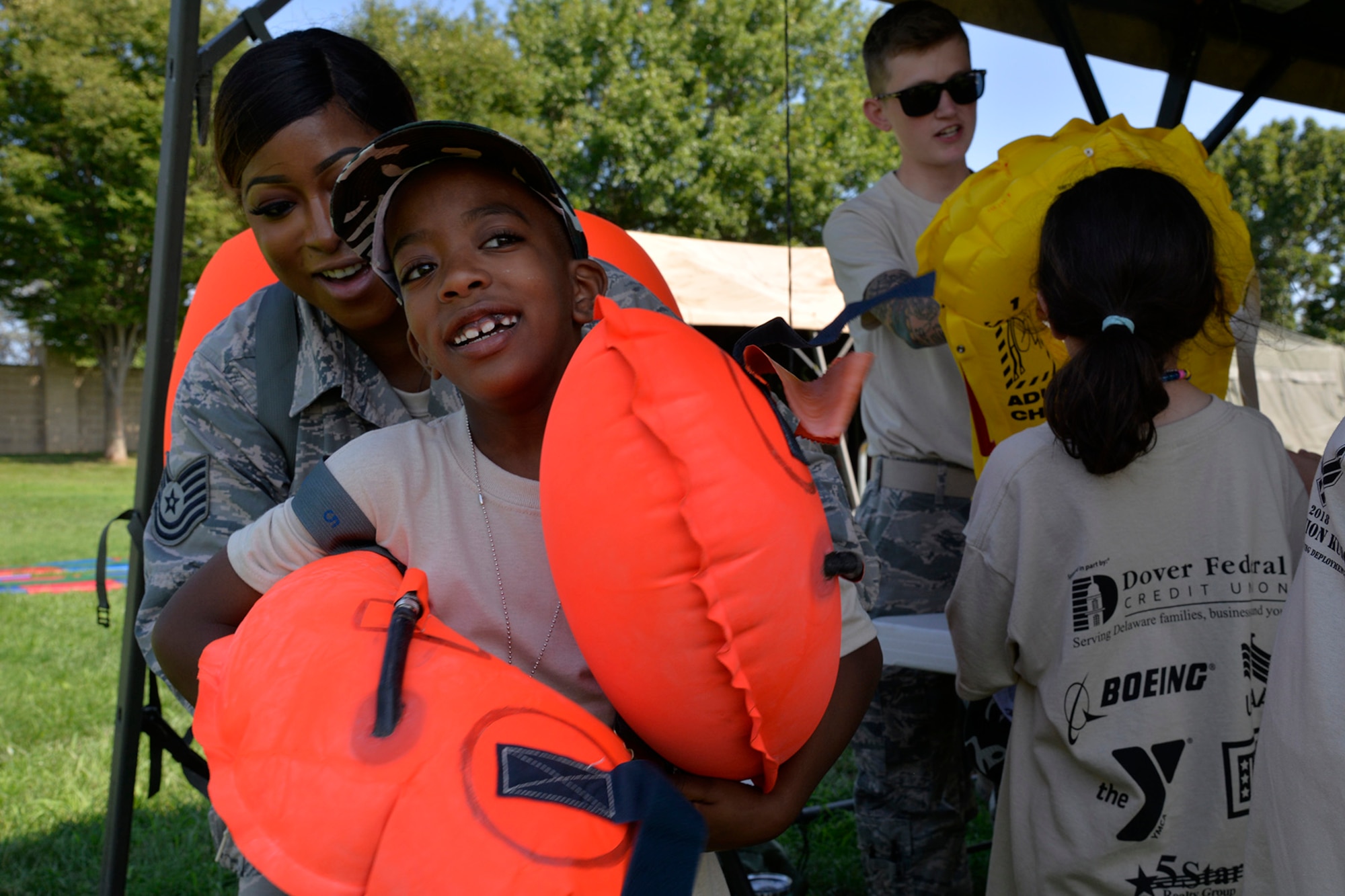 Tech. Sgt. Shante Doncits, 436th Operations Support Squadron aircrew flight equipment NCO in charge of production, shows children different types of aircrew flight equipment during a Kids/Teachers Understanding Deployment Operations event Aug. 9, 2018, at Dover Air Force Base, Del. Children and teachers learned about different support functions on base and how they contribute to the rapid global mobility mission. (U.S. Air Force photo by Tech. Sgt. Matt Davis)