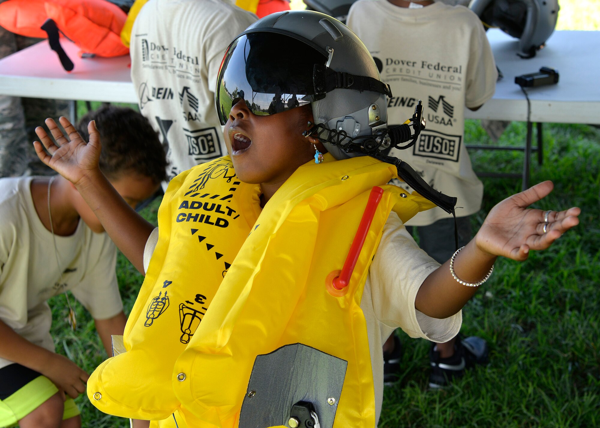 A child poses for a photo while wearing aircrew flight equipment during a Kids/Teachers Understanding Deployment Operations event Aug. 9, 2018, at Dover Air Force Base, Del. Children and teachers learned about different support functions on base and how they contribute to the rapid global mobility mission. (U.S. Air Force photo by Tech. Sgt. Matt Davis)