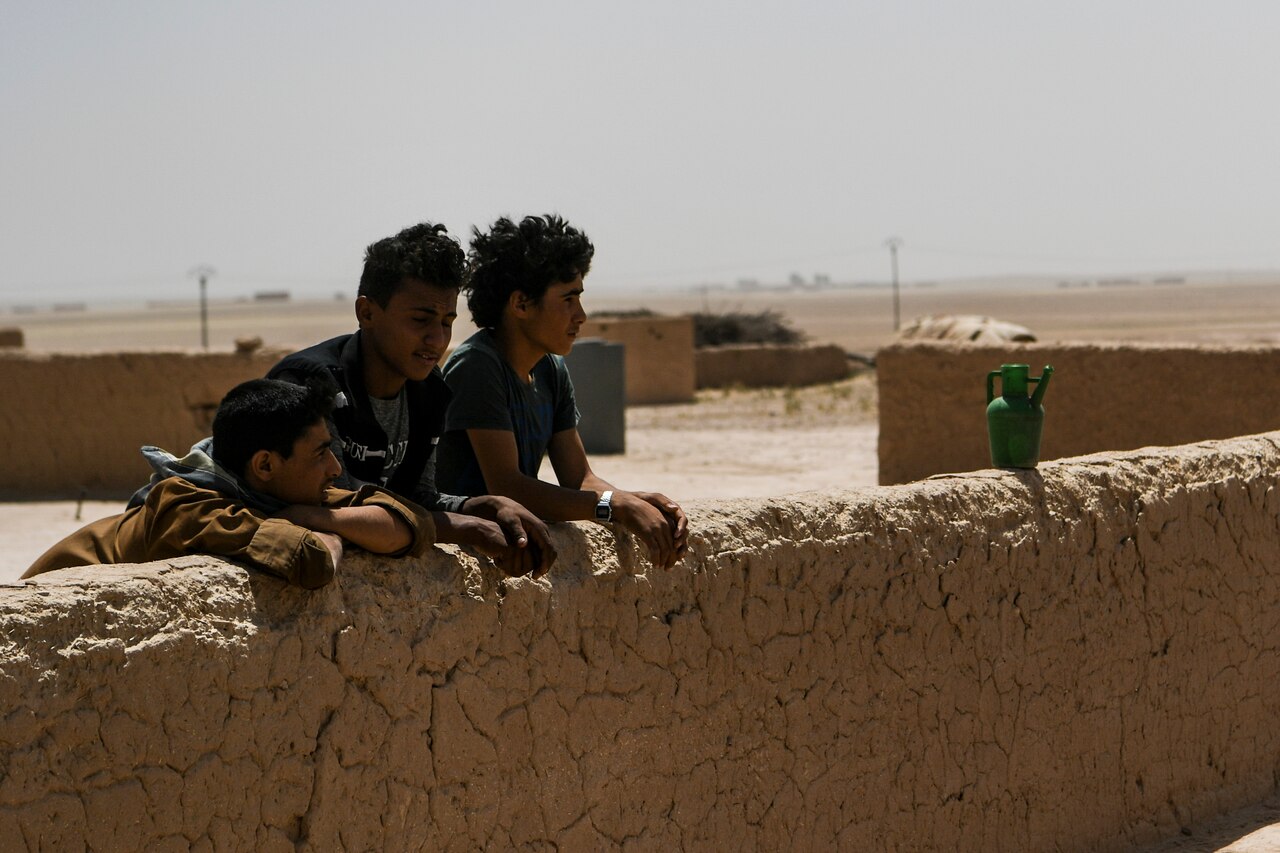 Children stand outside their home in a village near Dashisha, Syria.