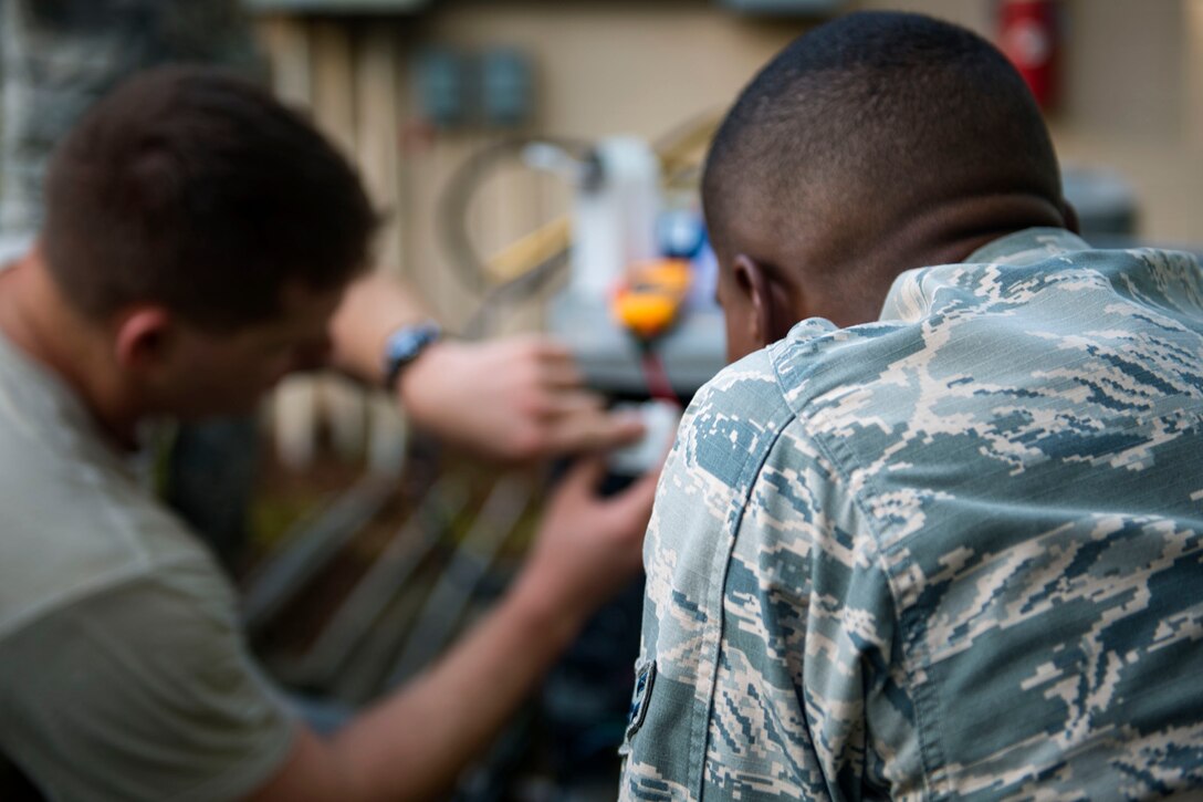 Staff Sgt. Edward Piotrkiewicz, left, 23d Civil Engineer Squadron (CES) Heating, Ventilation and Air Conditioning (HVAC) craftsman, explains the functionality of a component for a condenser unit to Airman 1st Class Jared King, 23d CES water and fuel system maintenance apprentice, during the “A Day In A Life” program, Aug. 9, 2018, at Moody Air Force Base, Ga. The program challenges participating civil engineers to go behind-the-scenes to perform multiple jobs to better understand their fellow Airmen and better develop operational leaders. Airmen from the 23d CES who work in the HVAC shop ensure the maintenance and restoration of the heating and cooling equipment around base. (U.S. Air Force photo by Airman 1st Class Erick Requadt)