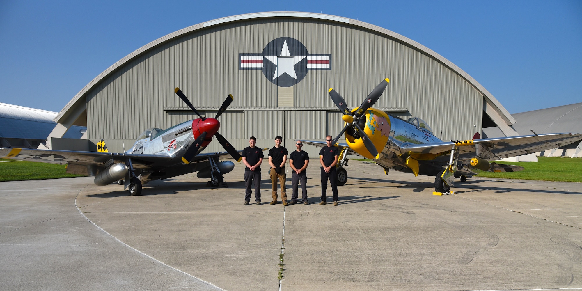 Museum restoration specialists(from left to right) Nick Almeter, Casey Simmons, Chase Meredith, and Brian Lindamood pose for a photo with the North American P-51D Mustang and the Republic P-47D (Bubble Canopy Version) at the National Museum of the U.S. Air Force on Aug. 14, 2018. They are well versed in a variety of skills ranging from machine and woodworking expertise to precision craftsmanship in sheet metal and painting. Their knowledge of aircraft spans years of technology -- from World War I fabric covered aircraft to the elite fighters of today's Air Force. (U.S. Air Force photo by Ken LaRock)
