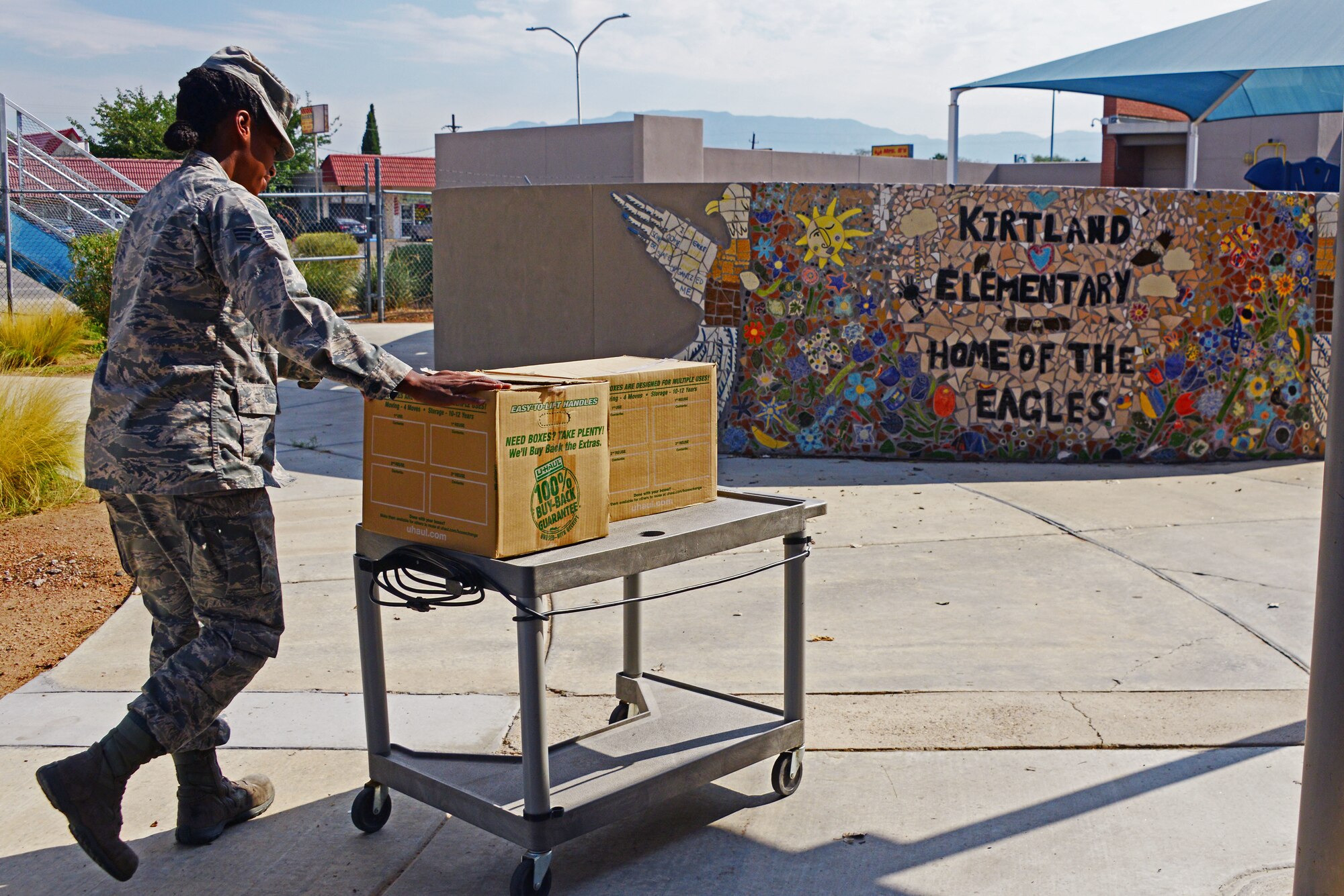 Senior Airman Roslyn Lack of the Space and Missile Systems Center’s Advanced Systems and Development Directorate brings donated supplies inside during a school supply drop at Kirtland Elementary here Aug. 10. Lack and other members of SMC AD dropped 1020 lbs. of supplies donated by the Kirtland community. The drive is conducted annually by local units under AFSPC. (U.S. Air Force photo by Jessie Perkins)