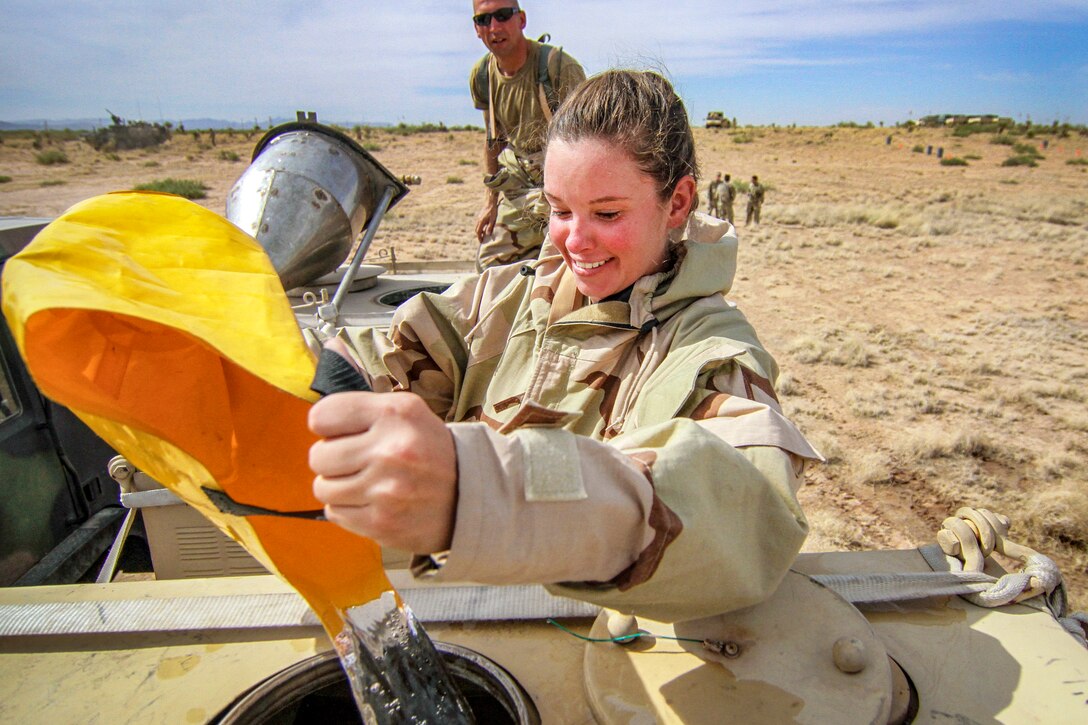 A reserve soldier pours water from a bucket into a device.