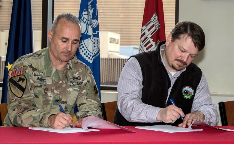 Col. Michael Brooks, commander of the U.S. Army Corps of Engineers - Alaska District, and Joe Balash, U.S. Department of the Interior’s Assistant Secretary of Land and Minerals Management, sign the first joint record of decision nationwide Aug.13 between the Corps and the Bureau of Land Management for the Donlin Gold mine project during a signing ceremony at the district headquarters building on Joint Base Elmendorf-Richardson.  Donlin Gold representatives also signed and received the applicable authorizations at the event.